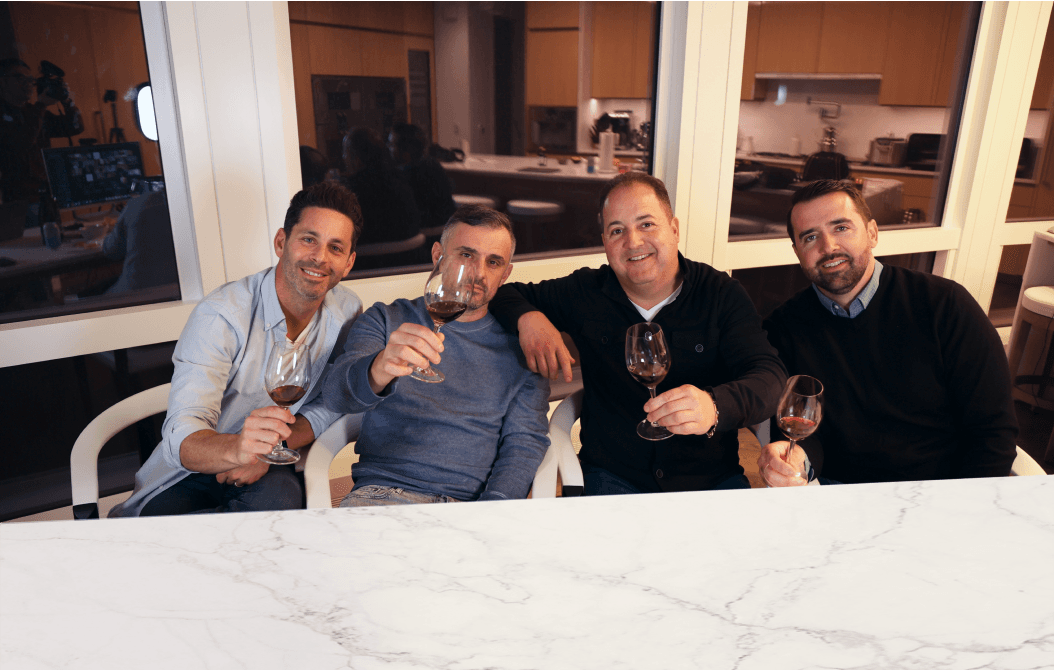 Photo of Gary holding bottles of wine in front of a wall of wine