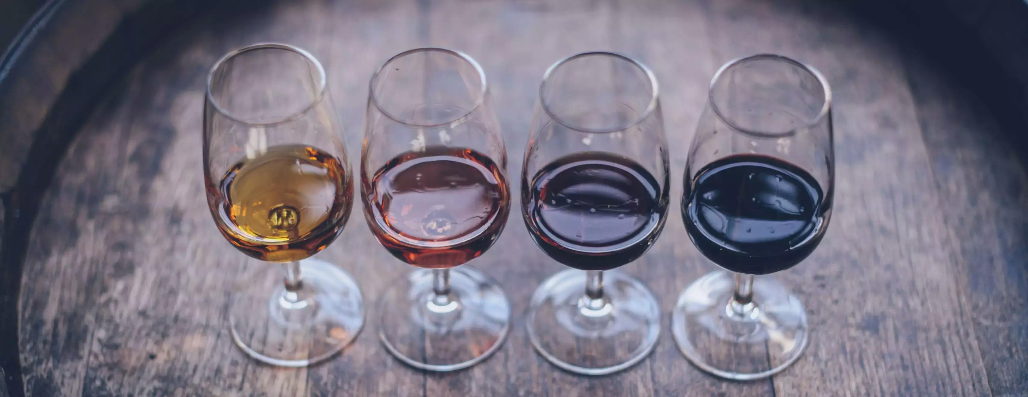 4 glasses of assorted wines on a wooden barrel top